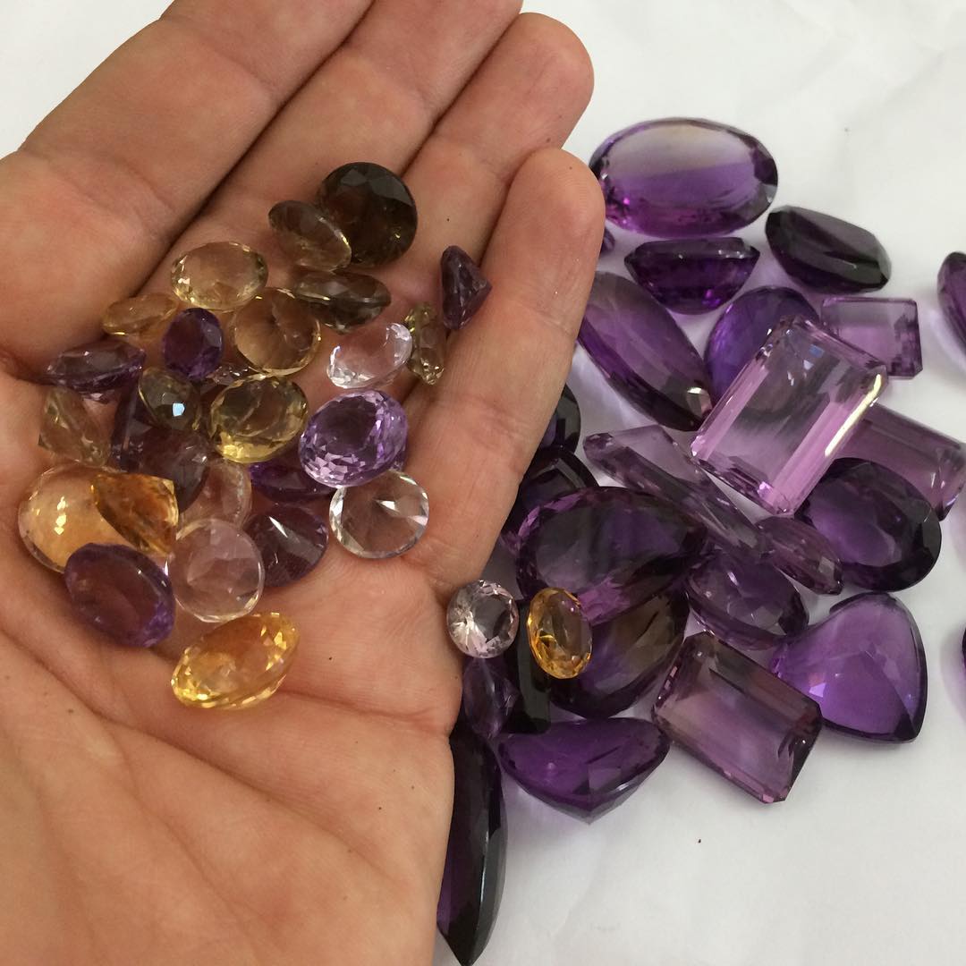 Amethyst and citrine gemstones arranged on a hand and white surface