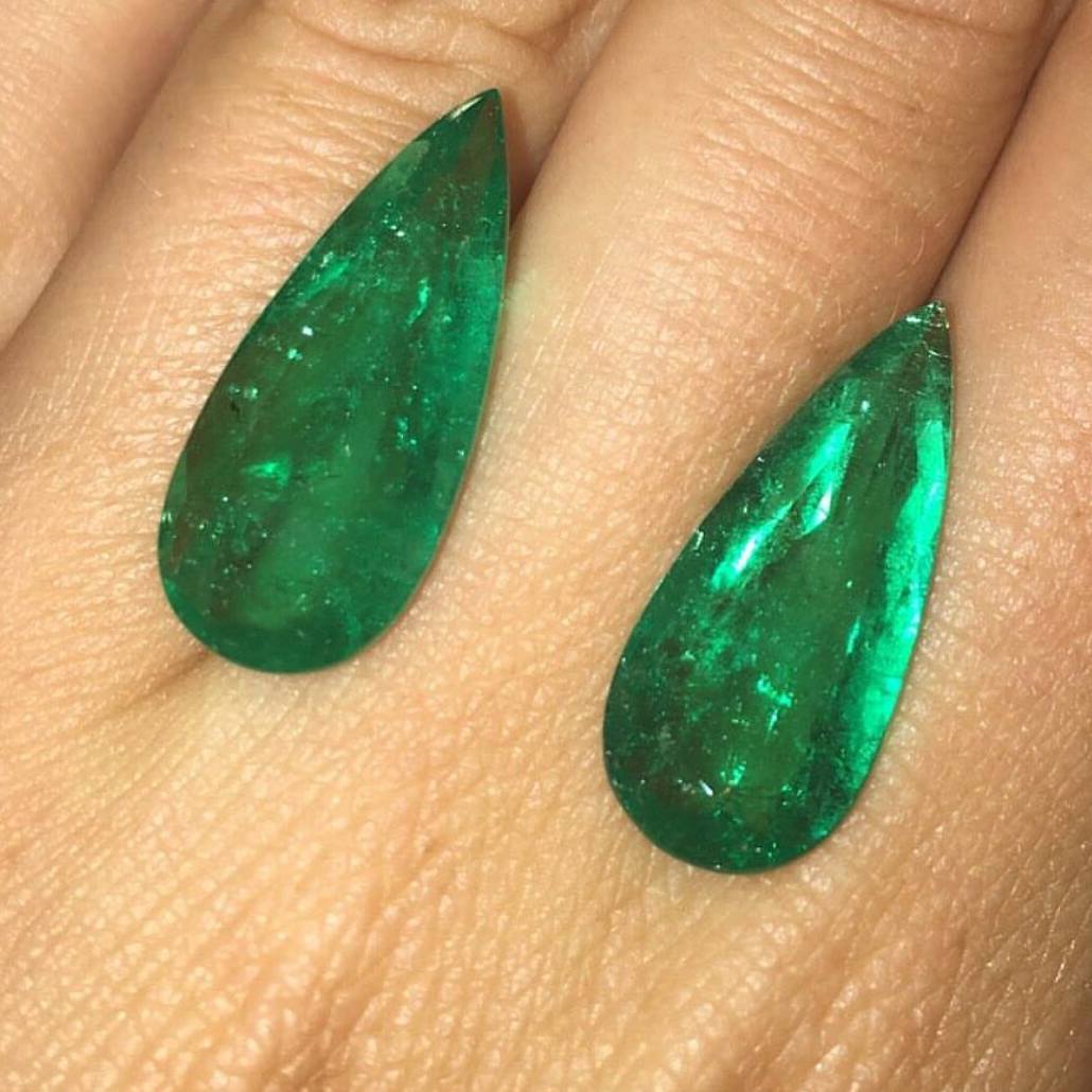 Pair of pear shaped emerald cabochons on hand