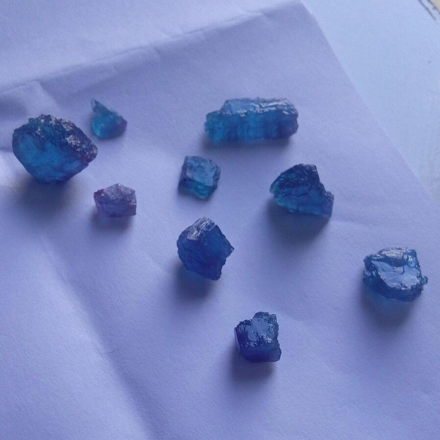 Rough blue tourmaline crystals on white paper